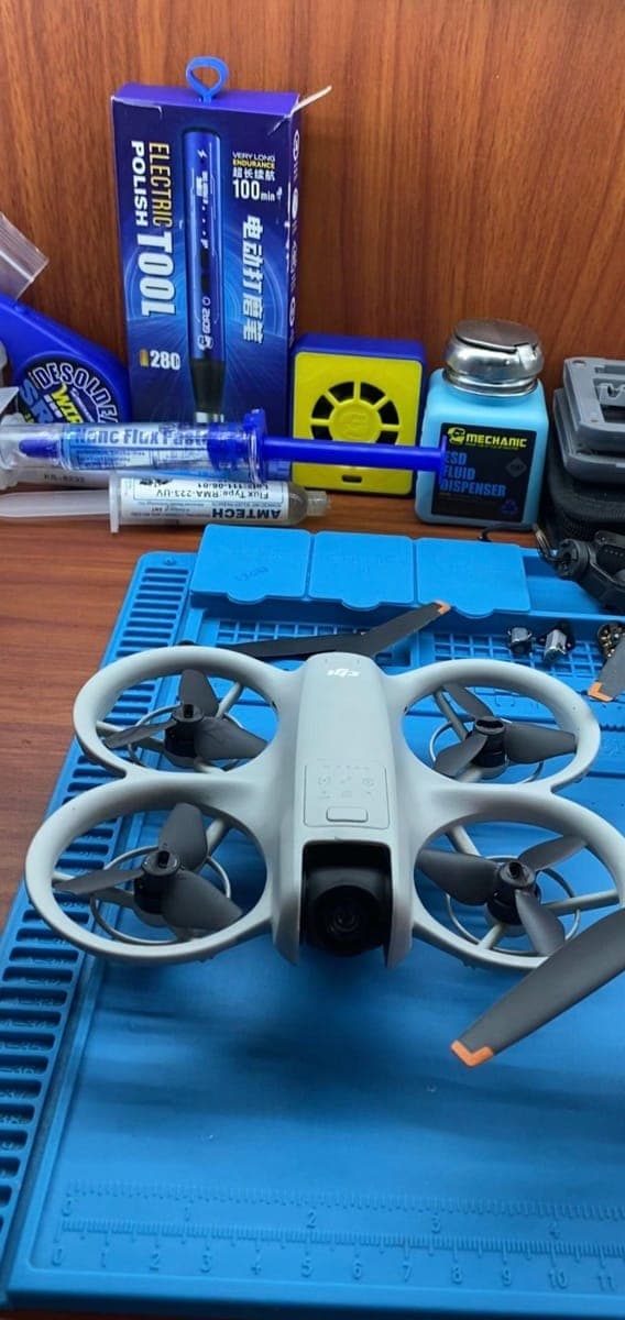 A DJI drone on the repair mat surrounded by soldering and repair tools